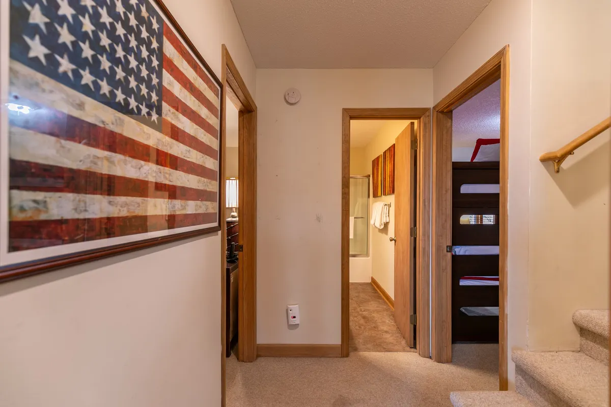 An inviting entryway with American flag artwork, doorways to other rooms, and a staircase. The layout shows open, level access, ideal for guests with mobility needs and offering an initial sense of welcome and accessibility.