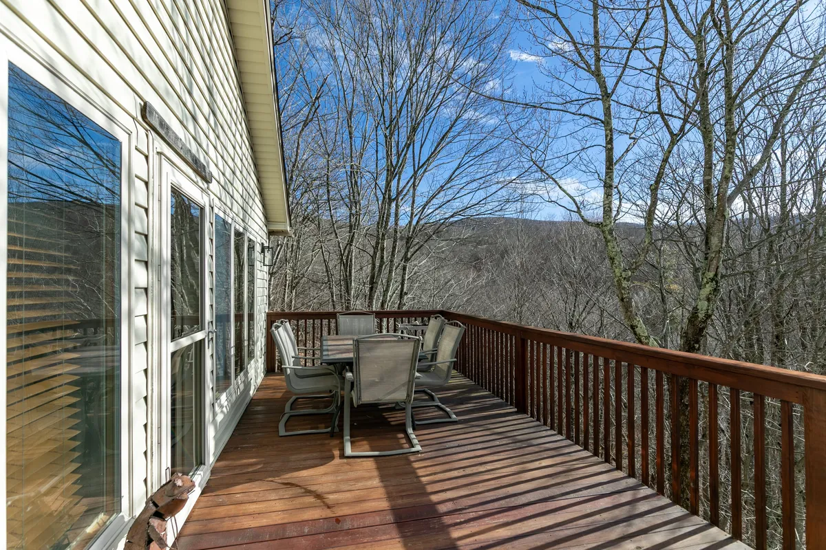 A tranquil exterior view of the deck features inviting seating arranged to take full advantage of the expansive mountain landscape. Trees frame the scene, creating a sense of privacy and immersion in nature—perfect for both daytime relaxation and evening stargazing.